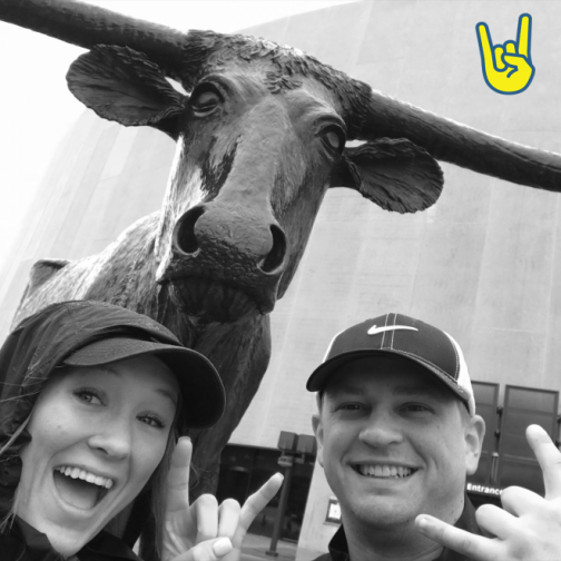 A couple posing with the #BuckOffDiabetes pose alongside a statue of a cow.