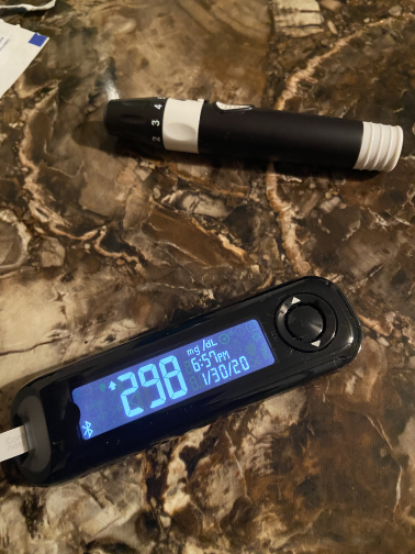 A finger lancet and a blood glucose monitor reading 298.
