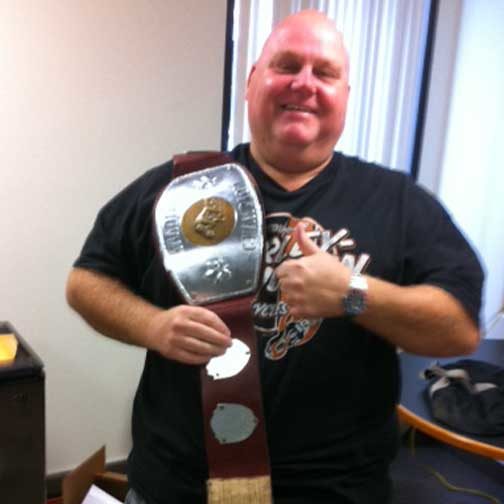 Dan Denton poses with a heavyweight wrestling champion belt. 